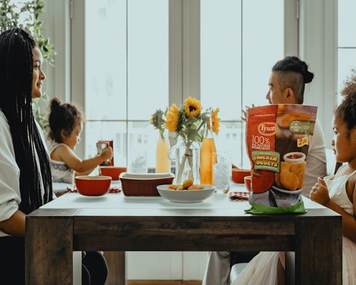 A family sitting at a dining table, reviewing a household budgeting checklist together