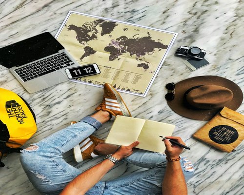 A person viewing a world map and a currency basics guide on their laptop